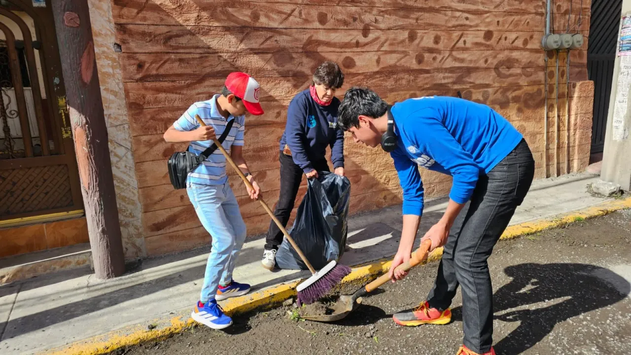 Personas realizando labores de limpieza en una calle de Toluca