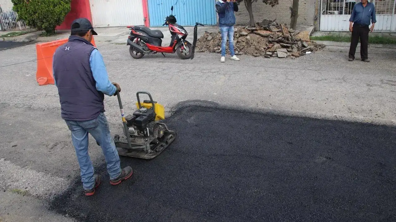 Maquinaria y trabajadores realizando labores de bacheo en una vialidad urbana