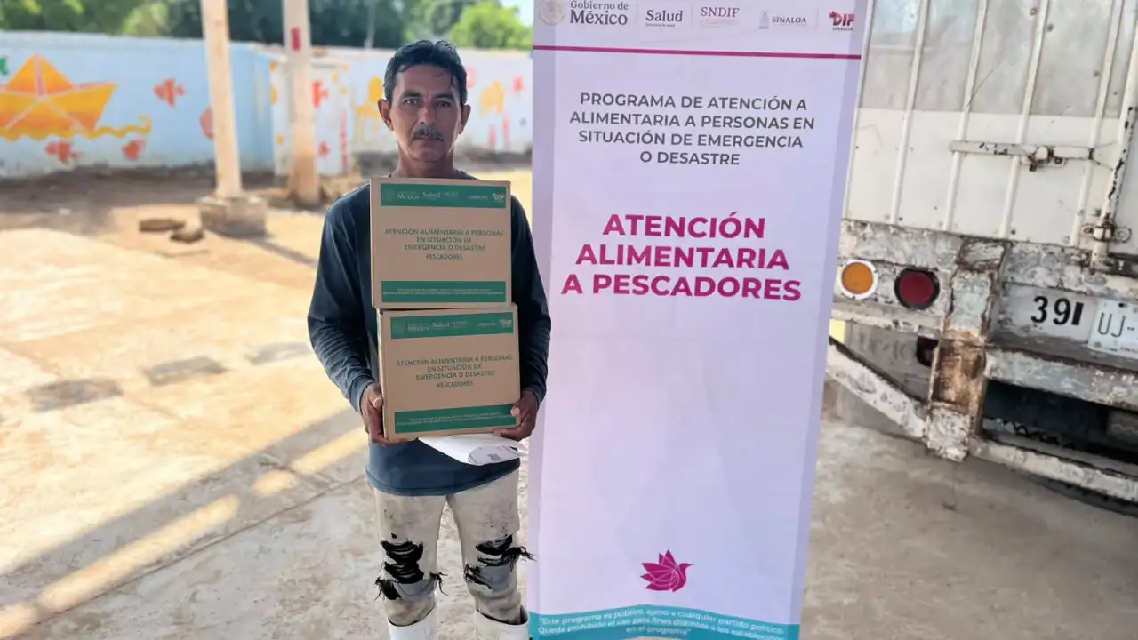 Pescadores reunidos durante la entrega de canastas alimenticias en un campo pesquero de Sinaloa