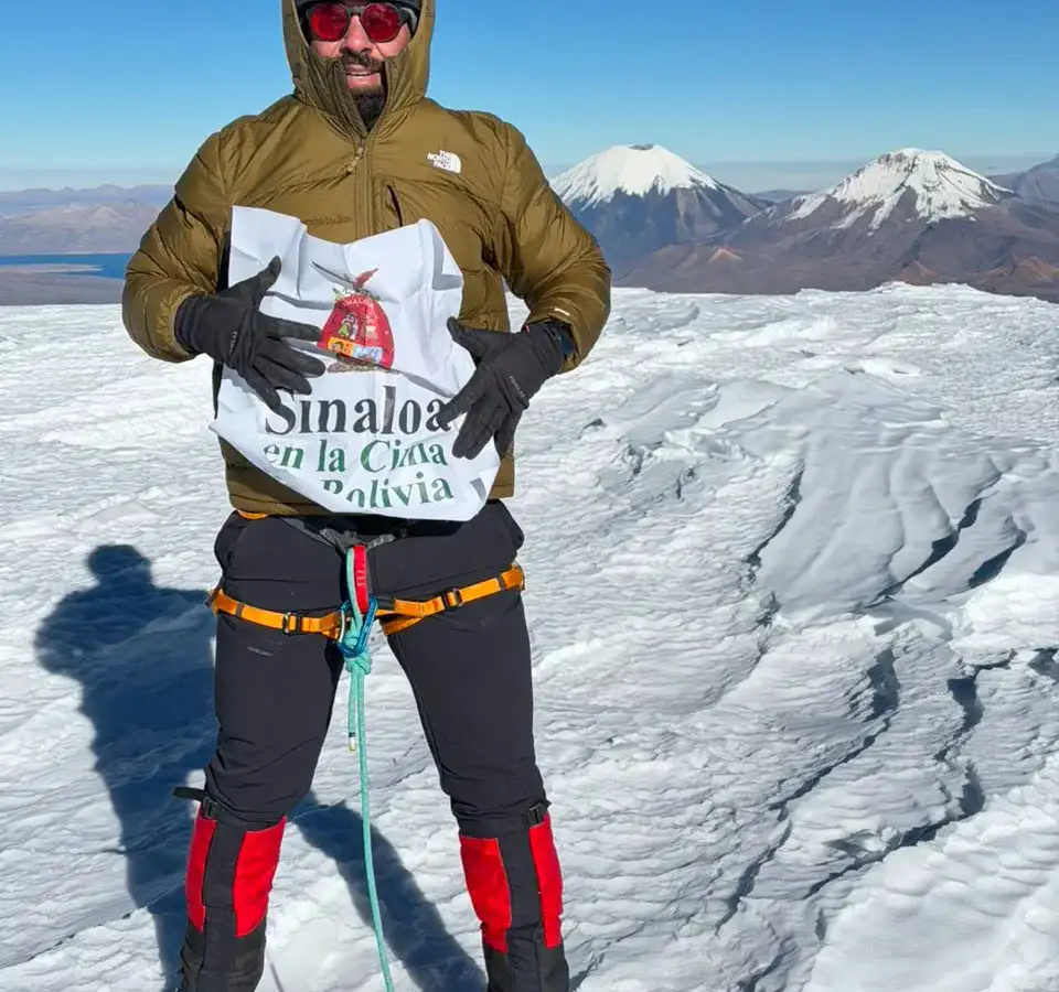 Alpinista en la cima nevada del Nevado Sajama con cielo azul