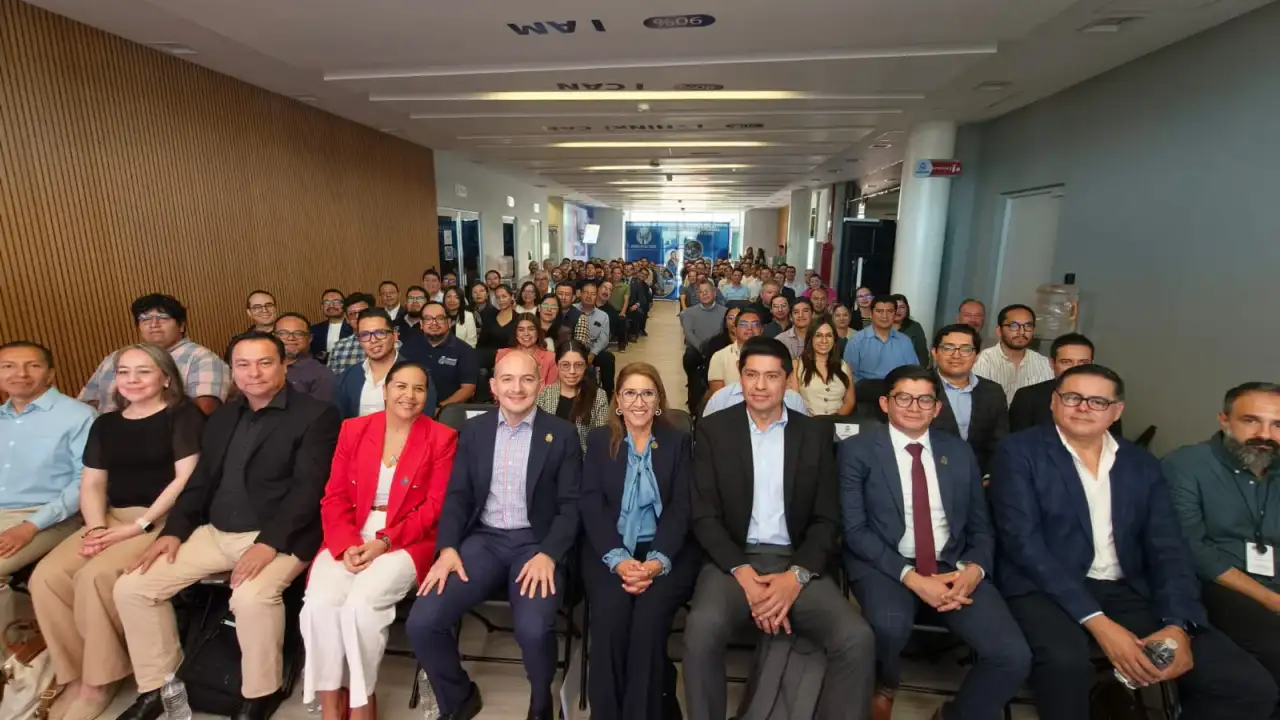 Personas reunidas en un foro sobre inteligencia artificial en un salón con pantallas y mesas