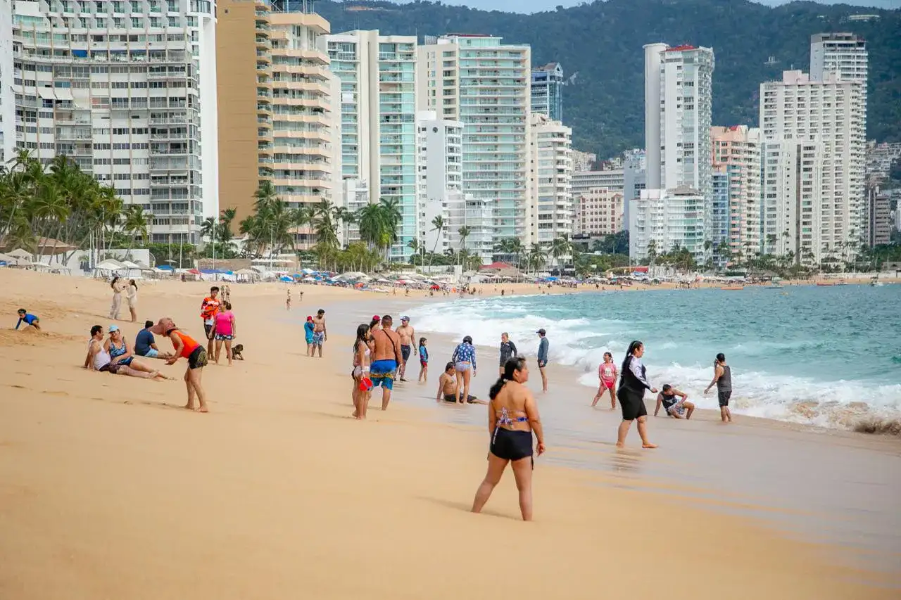 Turistas caminando por la zona costera de un destino de playa en Guerrero