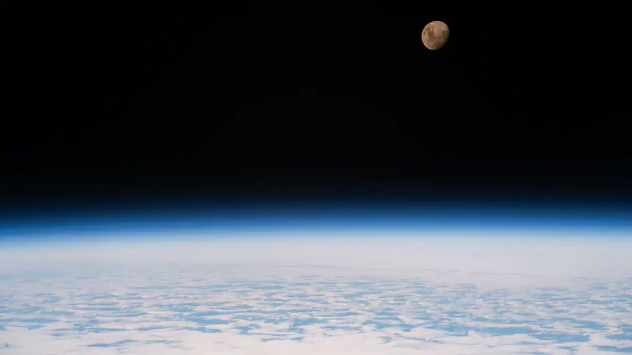 Luna gibosa creciente vista desde la ISS contra el espacio oscuro, con la superficie iluminada parcialmente.