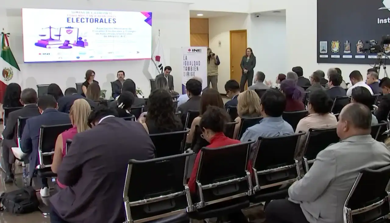 Reunión de representantes electorales en un salón con banderas de México