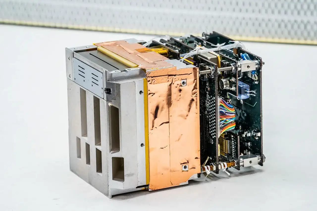 Ilustración del instrumento REAL montado en un CubeSat realizando mediciones de partículas energéticas.