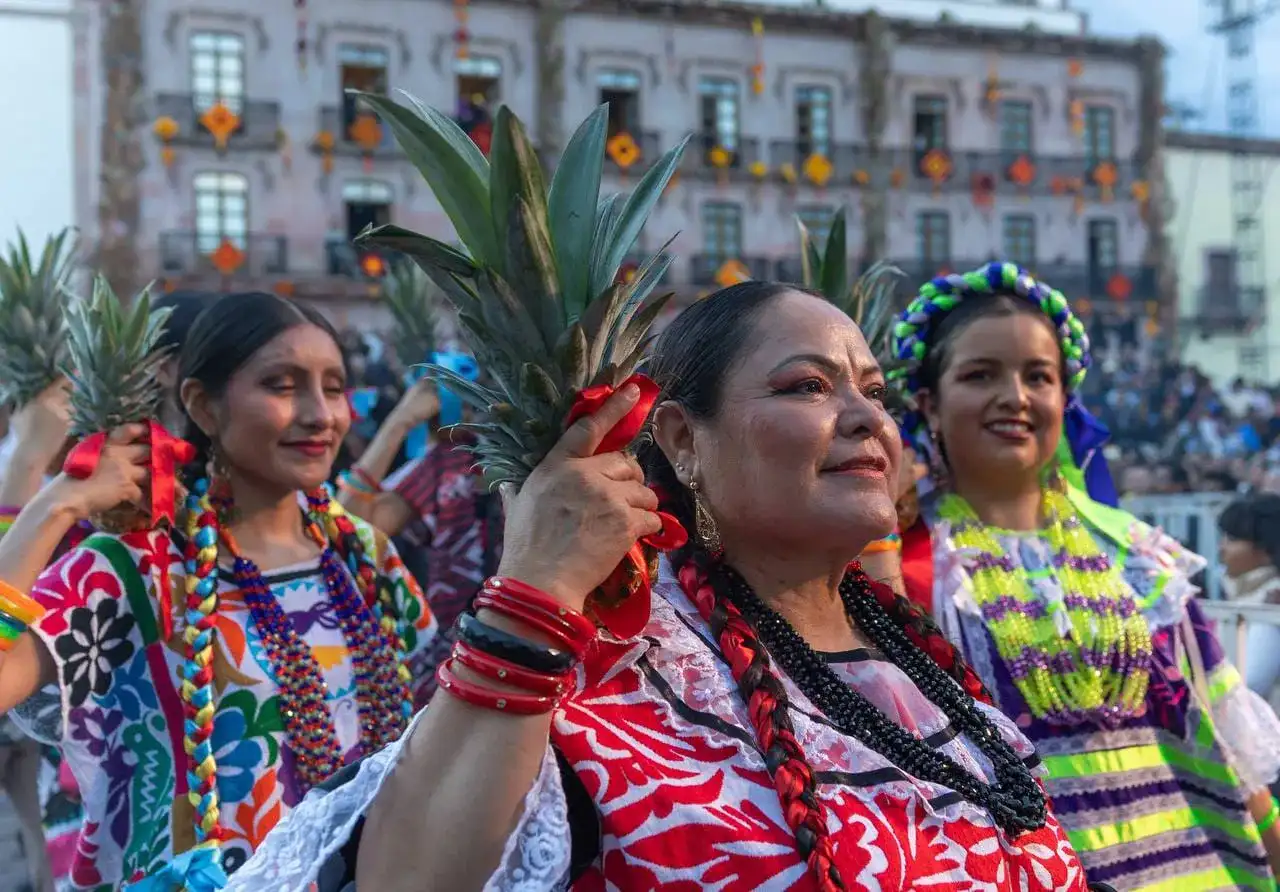 Personas con trajes tradicionales durante un desfile cultural en una plaza