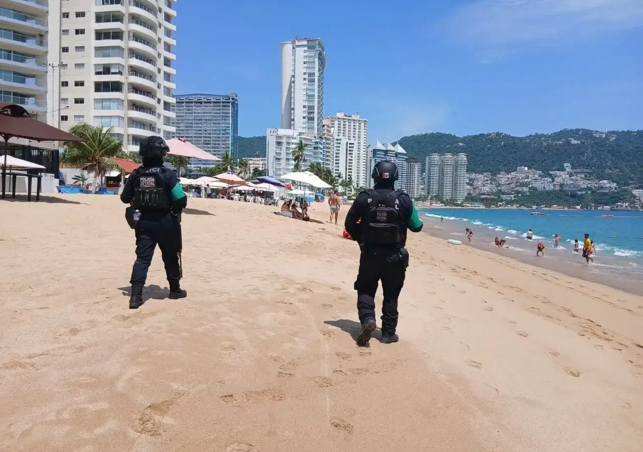 Agentes de la Policía Ecológica Estatal caminan por una playa de Acapulco durante un recorrido de proximidad social.