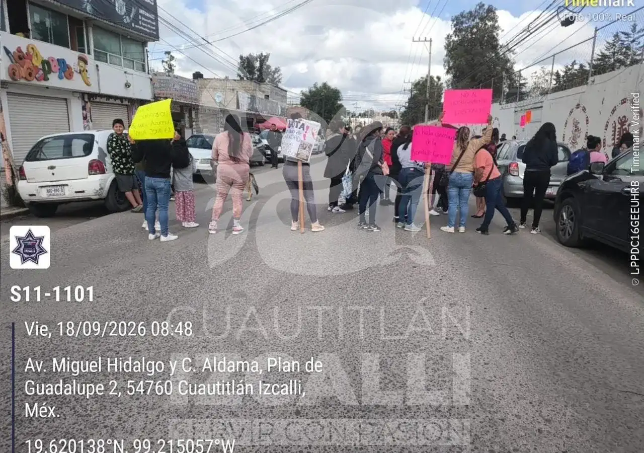 Personas concentradas sobre una avenida frente a una escuela primaria