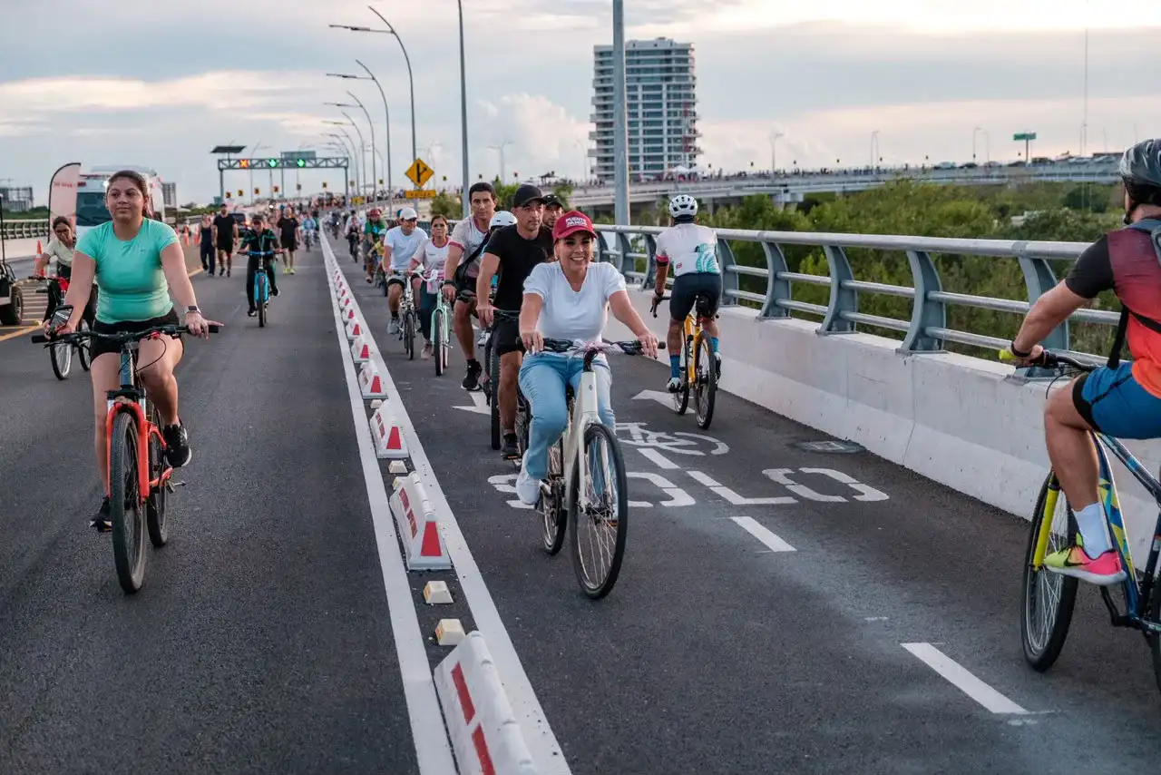 Personas caminando y en bicicleta sobre el puente de la Laguna Nichupté en Cancún