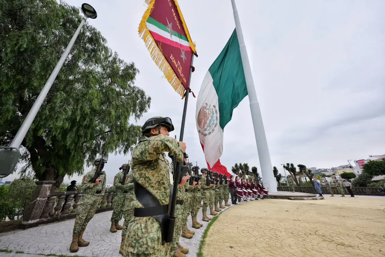 Autoridades y asistentes durante una ceremonia cívica con bandera de México en Querétaro