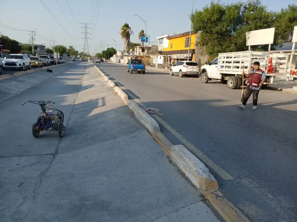 Trabajadores municipales pintan señalización vial en una avenida de Reynosa