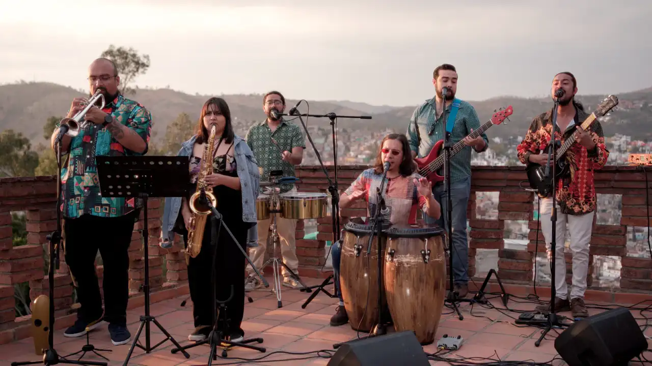 Personas bailando al aire libre durante un concierto de salsa en un jardín