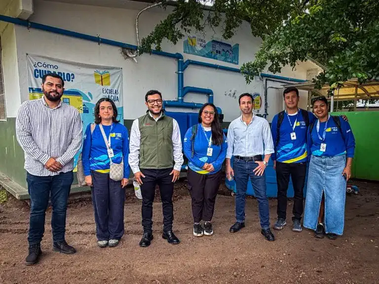 Estudiantes y personal escolar junto a un sistema de captación de agua de lluvia
