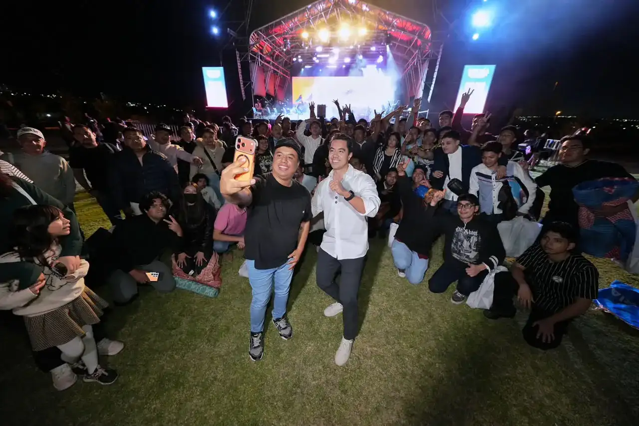 Personas reunidas en un parque durante un concierto al aire libre por la noche