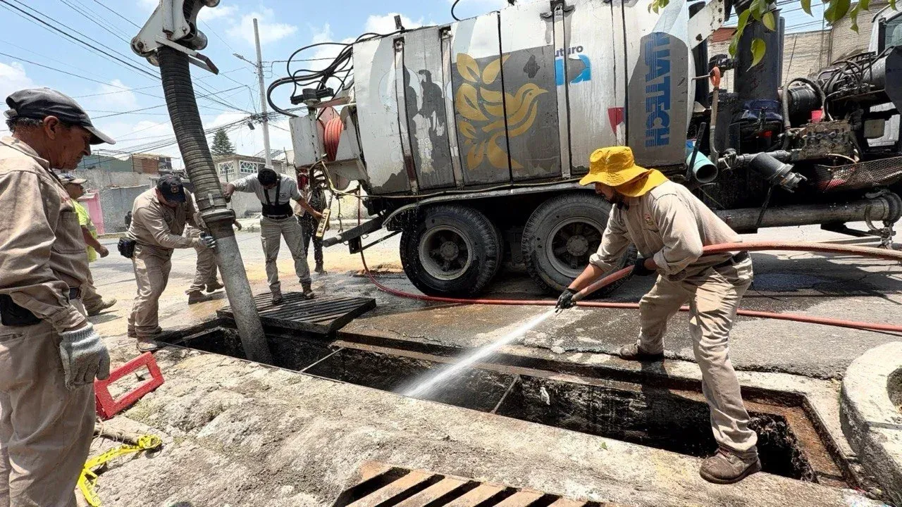 Trabajadores de limpieza revisan una coladera en una calle de Cuautitlán Izcalli