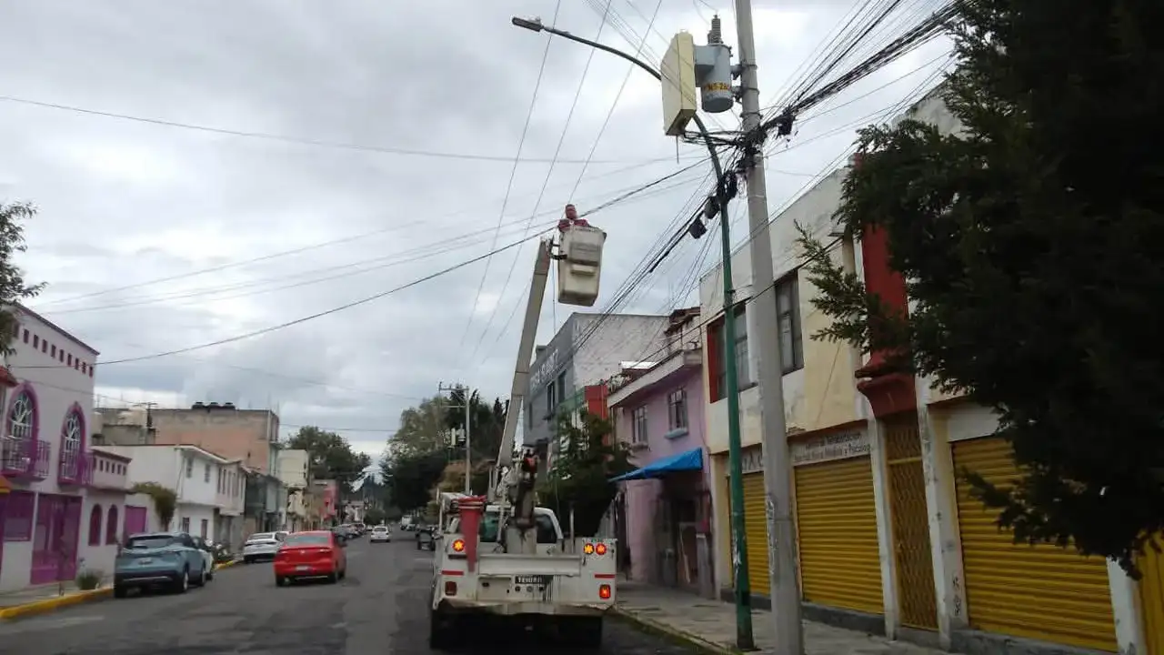 Trabajadores instalan luminarias LED en una calle de Toluca