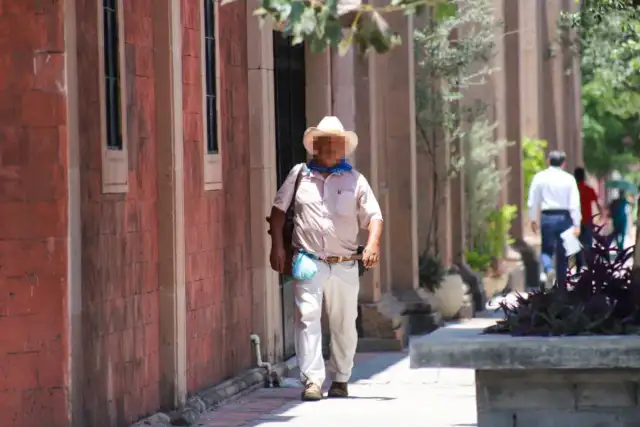 Persona usando sombrero y bebiendo agua bajo el sol en Tamaulipas