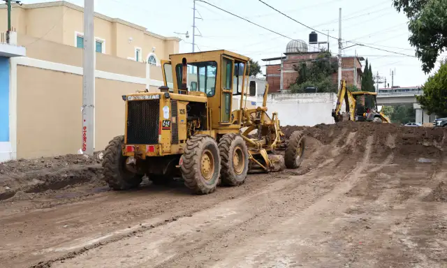 Obras de pavimentación en una calle de Toluca con maquinaria y trabajadores.