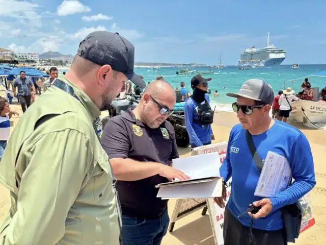 Vista de playa El Médano en Cabo San Lucas, con turistas y sombrillas