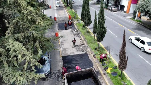 Trabajadores de bacheo en una calle de Toluca con maquinaria y señalamientos