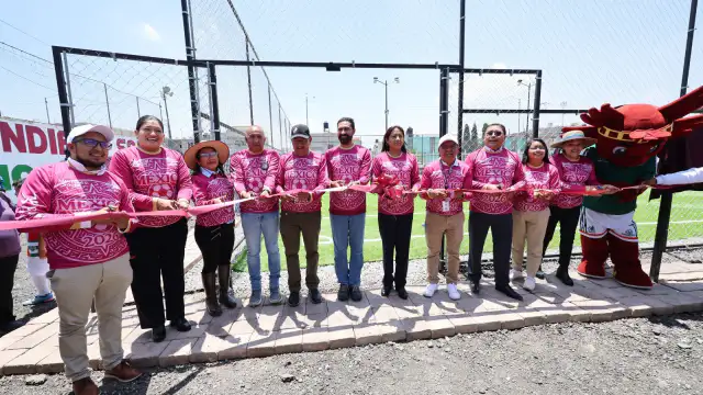 Mujer alcaldesa corta listón en una cancha de fútbol con niños presentes