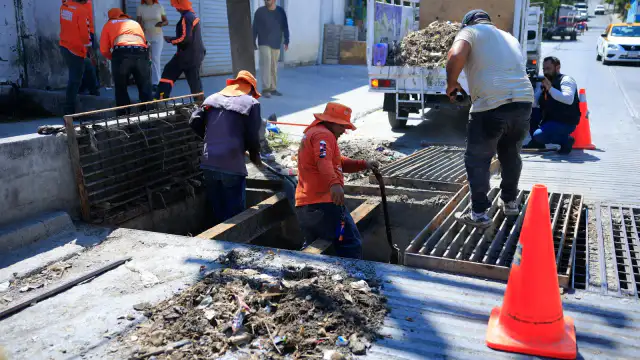 Trabajadores municipales limpiando una rejilla pluvial en una calle de Guadalupe