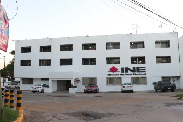 Personas consultando una convocatoria electoral en una oficina del INE
