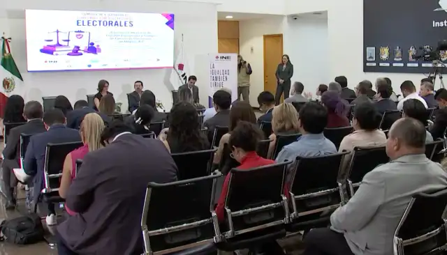 Reunión de representantes electorales en un salón con banderas de México