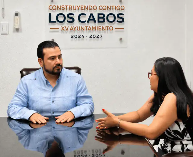 Reunión entre autoridades municipales y arquitectos en una sala de juntas con plano urbano de fondo