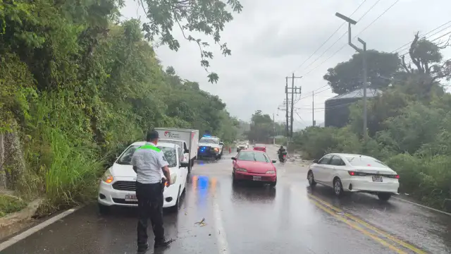 Agente de tránsito dirige el tráfico en una calle con lluvia en Acapulco