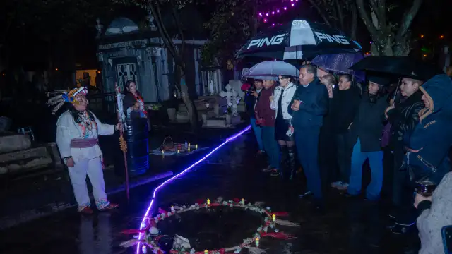 Personas caminando de noche entre tumbas durante un recorrido de leyendas en un panteón