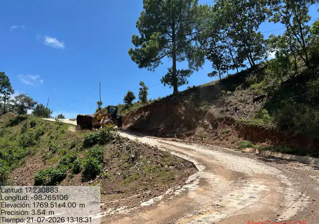Maquinaria pesada removiendo escombros en carretera de montaña.