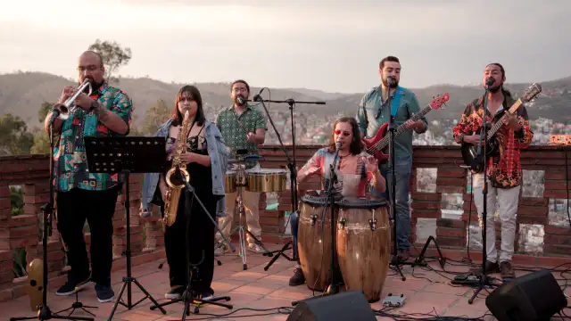 Personas bailando al aire libre durante un concierto de salsa en un jardín