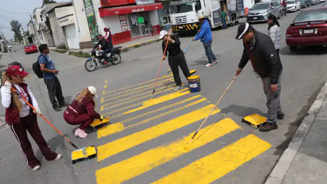 Vecinos y servidores públicos durante labores de limpieza en una calle de Toluca