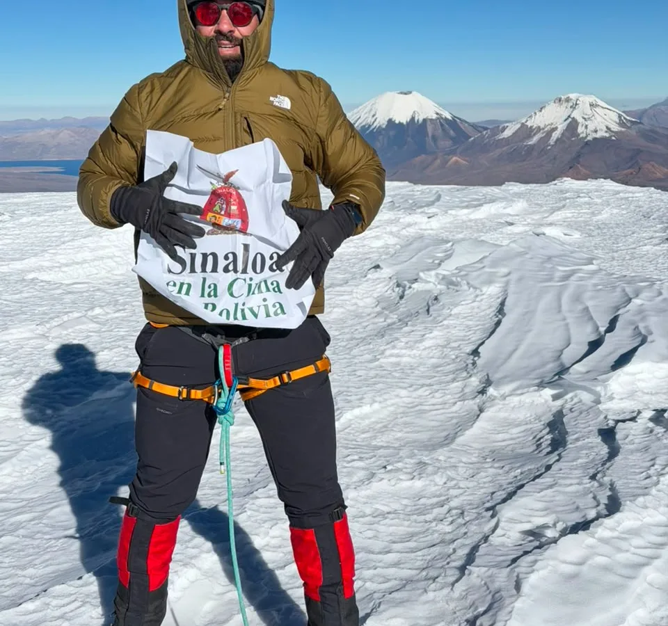 Alpinista en la cima nevada del Nevado Sajama con cielo azul